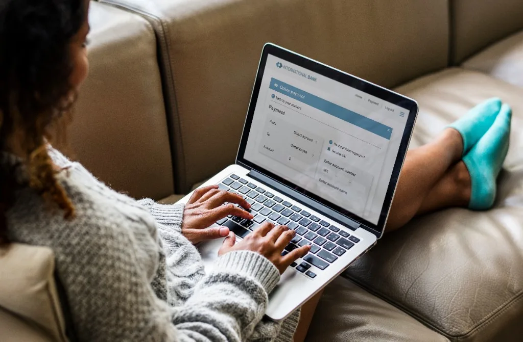 Person on a couch using a laptop with an online payment screen